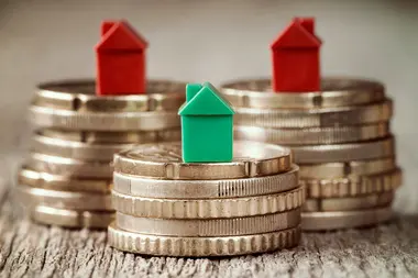 Miniature houses resting on coins stacks. Concept for property ladder, mortgage and real estate investment